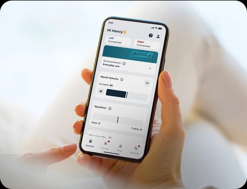 Hand holding a phone adjusting settings for the Lexie B1 hearing aids on the Lexie app.